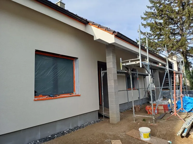 Bungalov s novou fasádou a oranžovými rámami okien v lešení