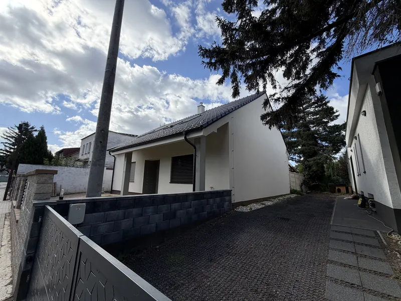 Dokončený dom s bielou fasádou, pohľad od príjazdovej cesty